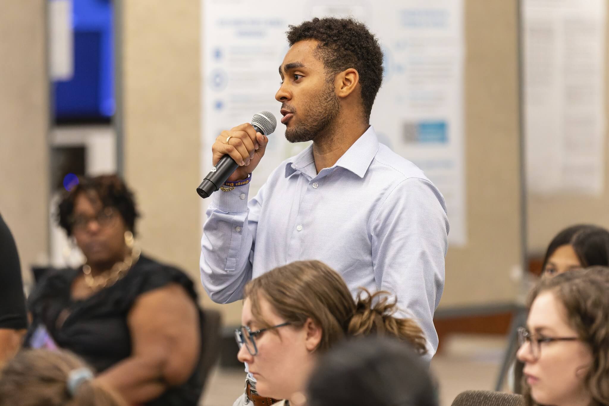 A young man speaking into a microphone in an audience